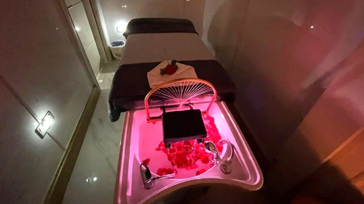 Εσωτερικό ενός ζεστού δωματίου Japanese Head Spa με χαμηλό φωτισμό, με κρεβάτι θεραπείας, νιπτήρα με πέταλα και εξοπλισμό spa
