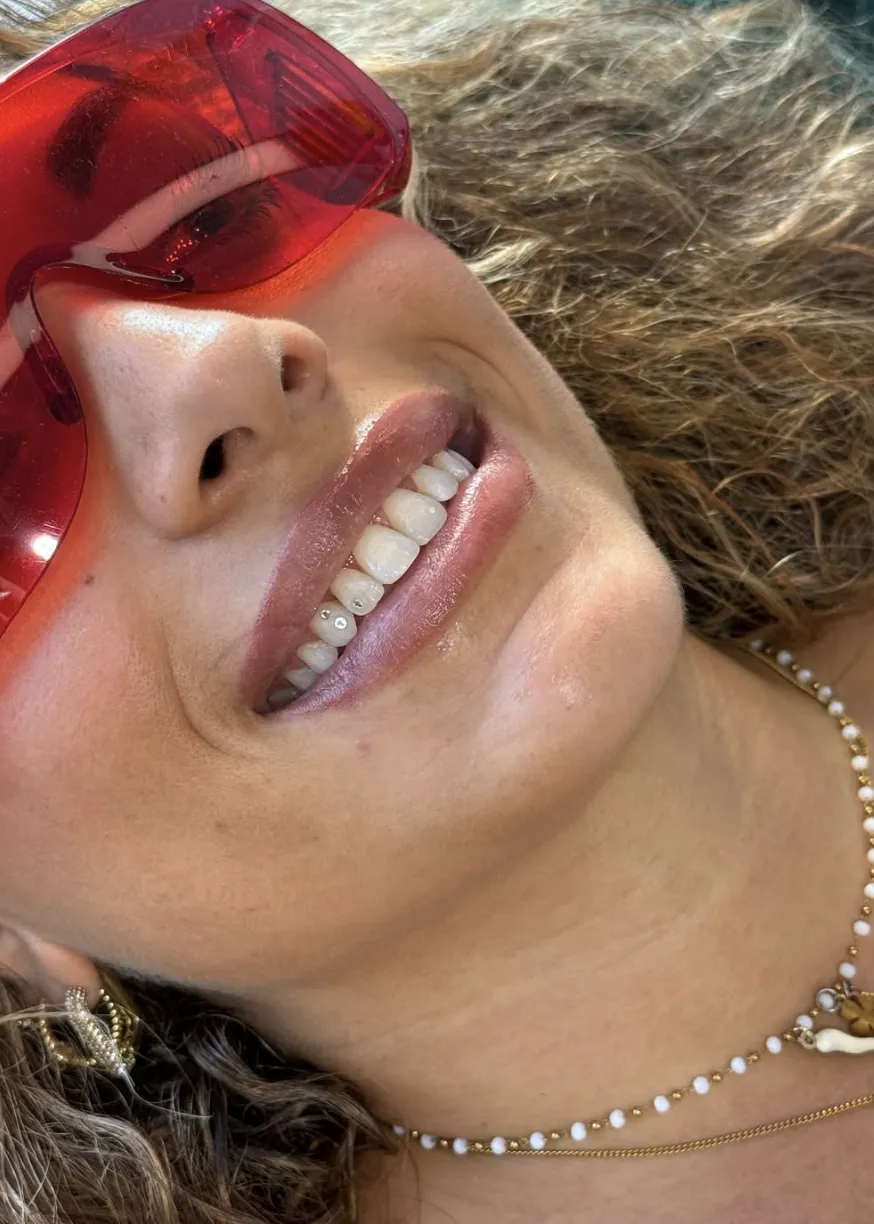 Κοντινό πλάνο σε χαμόγελο με δύο μικρά tooth gems από κρύσταλλο στα κάτω δόντια, καλοκαιρινό πορτρέτο